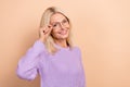 Photo of cheerful clever smart retired lady blond hairdo wear knit sweater hands touching eyewear isolated on beige