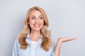 Photo of cheerful curious lady hand presenting empty space wear blue shirt isolated grey color background