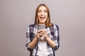 Photo of cheerful cute beautiful young woman chatting by mobile phone isolated over grey wall background Royalty Free Stock Photo