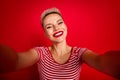 Photo of cheerful cute girl wearing trendy clothes shooting recording video vlog isolated on red color background Royalty Free Stock Photo