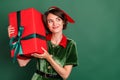 Photo of cheerful dreamy lady hold box look empty space wear elf costume hat isolated green color background