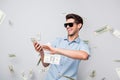 Photo of cheerful excited ecstatic overjoyed man throwing money away showing his wealthiness wearing denim isolated over Royalty Free Stock Photo