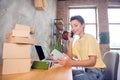 Photo of cheerful excited lady sit desktop unpacking case boxes make call wear yellow t-shirt in modern house indoors