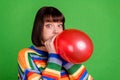 Photo of cheerful funky childish young woman hold hands balloon blow air isolated on green color background Royalty Free Stock Photo