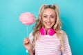 Photo of cheerful funky girl hold puffy cotton candy stick headphones hang neck isolated on teal color background Royalty Free Stock Photo