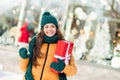 Photo of cheerful funny school girl dressed outwear coat holding x-mas gift modern device outdoors urban city street