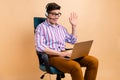 Photo of cheerful glad guy sitting office chair speaking saying hello earphones microphone video call  on beige Royalty Free Stock Photo