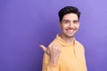 Photo of cheerful good mood guy wear yellow polo showing thumb back empty space isolated violet color background