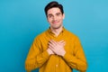 Photo of cheerful grateful guy hands chest heart form wear yellow shirt isolated blue color background