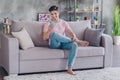 Photo of cheerful guy hold telephone sit couch read post wear casual outfit in comfortable apartment home indoors