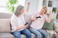 Photo of cheerful happy grey haired blonde women sit sofa win game hold joystick indoors inside house home Royalty Free Stock Photo