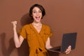 Photo of cheerful happy victorious woman hold hands laptop winner good mood business isolated on brown color background