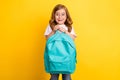 Photo of cheerful impressed school girl wear white t-shirt spectacles holding rucksack smiling yellow color