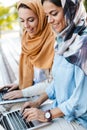 Photo of cheerful islamic girls wearing headscarfs studying in park