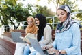 Photo of cheerful islamic women wearing headscarfs resting in green park Royalty Free Stock Photo