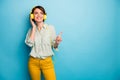 Photo of cheerful lady listen radio stylish earphones raise finger indicating empty space wear casual green shirt yellow