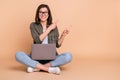 Photo of cheerful lady sit floor hold pc indicate finger empty space sale wear khaki shirt  beige color Royalty Free Stock Photo