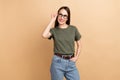 Photo of cheerful lady wearing khaki t shirt touch eyeglasses brainstorming looking novelty idea isolated on beige color Royalty Free Stock Photo