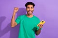 Photo of cheerful lucky man wear green t-shirt winning game apple samsung iphone modern gadget isolated purple color