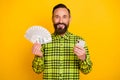 Photo of cheerful man happy positive smile use cellphone hold dollars cash money rich isolated over yellow color