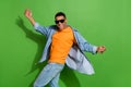 Photo of cheerful overjoyed active young man wear cool sunglass have fun dancing isolated on green color background