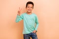 Photo of cheerful positive boy wear trendy clothes showing v-sign have fun good mood isolated on beige color background Royalty Free Stock Photo