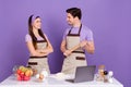 Photo of cheerful positive boyfriend girlfriend dressed chef outfits ready bake biscuits gadget isolated purple color