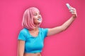 Photo of cheerful positive cute pretty attractive woman with pink hair taking selfie smiling toothily isolated over pink Royalty Free Stock Photo