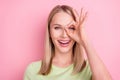 Photo of cheerful positive foolish lady make okey sign cover eye wear green t-shirt isolated on pink background Royalty Free Stock Photo