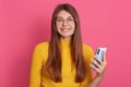 Photo of cheerful positive good looking young female posing isolated over pink background in studio, smiling sincerely, holding Royalty Free Stock Photo