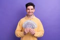 Photo of cheerful positive guy wear yellow polo holding money cash fan isolated violet color background Royalty Free Stock Photo