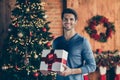 Photo of cheerful positive handsome man smiling toothily holding wrapped gift box present from santa claus standing in