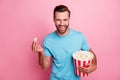 Photo of cheerful positive man watching tv series holding bucket of popcorn tasting smiling toothily comedy isolated in Royalty Free Stock Photo