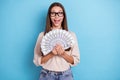 Photo of cheerful positive pretty wealthy lady hold cash usd wins lottery hooray isolated on blue color background