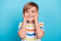 Photo of cheerful positive schoolboy hands cover ears wear striped t-shirt isolated blue color background