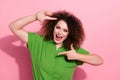 Photo of cheerful positive young woman dressed green shirt smiling showing hands photo frame isolated pink color Royalty Free Stock Photo