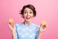 Photo of cheerful pretty girl tongue lick teeth arms hold two juicy lemon halves isolated on pink color background Royalty Free Stock Photo