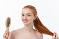 Photo of cheerful smiling freckled ginger young woman combs her long red hair, glad to prepare for date with boyfriend Royalty Free Stock Photo