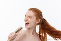 Photo of cheerful smiling freckled ginger young woman combs her long red hair, glad to prepare for date with boyfriend Royalty Free Stock Photo