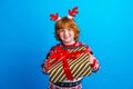 Photo of cheerful sweet little boy dressed ugly pullover horns giving x-mas present isolated blue color background Royalty Free Stock Photo