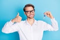 Photo of cheerful young attractive brunette man hold keys show thumb-up smile isolated on blue color background