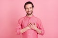 Photo of cheerful young attractive man hold hands heart good mood thankful isolated on pink color background