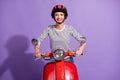 Photo of cheerful young girl ride retro bike toothy smile wear helmet striped shirt isolated violet color background Royalty Free Stock Photo