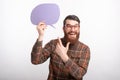Cheerful young man with beard wearing glasses and pointing at bubble speech Royalty Free Stock Photo