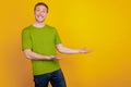 Photo of cheerful young man show object product promo two hands empty space isolated on yellow color background