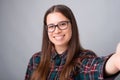 Photo of cheerful young woman with eyeglasses and taking selfie