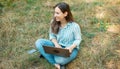 Photo of cheerful young woman sitting on gras in park and using laptop Royalty Free Stock Photo