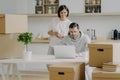 Photo of cheerful young woman stands behind her husband who works on laptop computer, pose in modern kitchen of their new