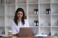 Photo of cheerful young woman working using computer laptop concentrated and smiling at office Royalty Free Stock Photo