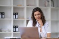 Photo of cheerful young woman working using computer laptop concentrated and smiling at office Royalty Free Stock Photo